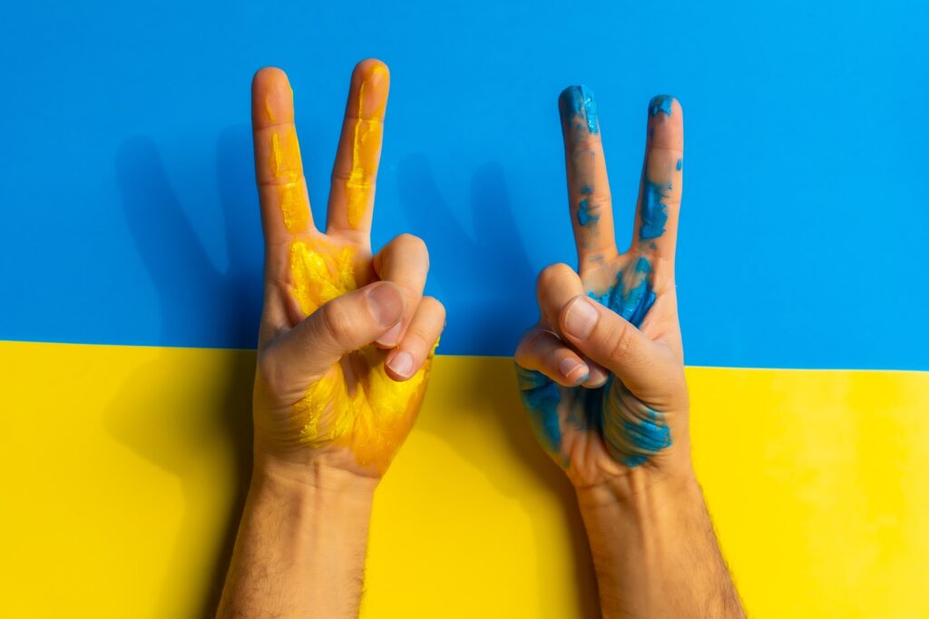 A man wearing the colors of the Ukrainian flag and making the victory sign